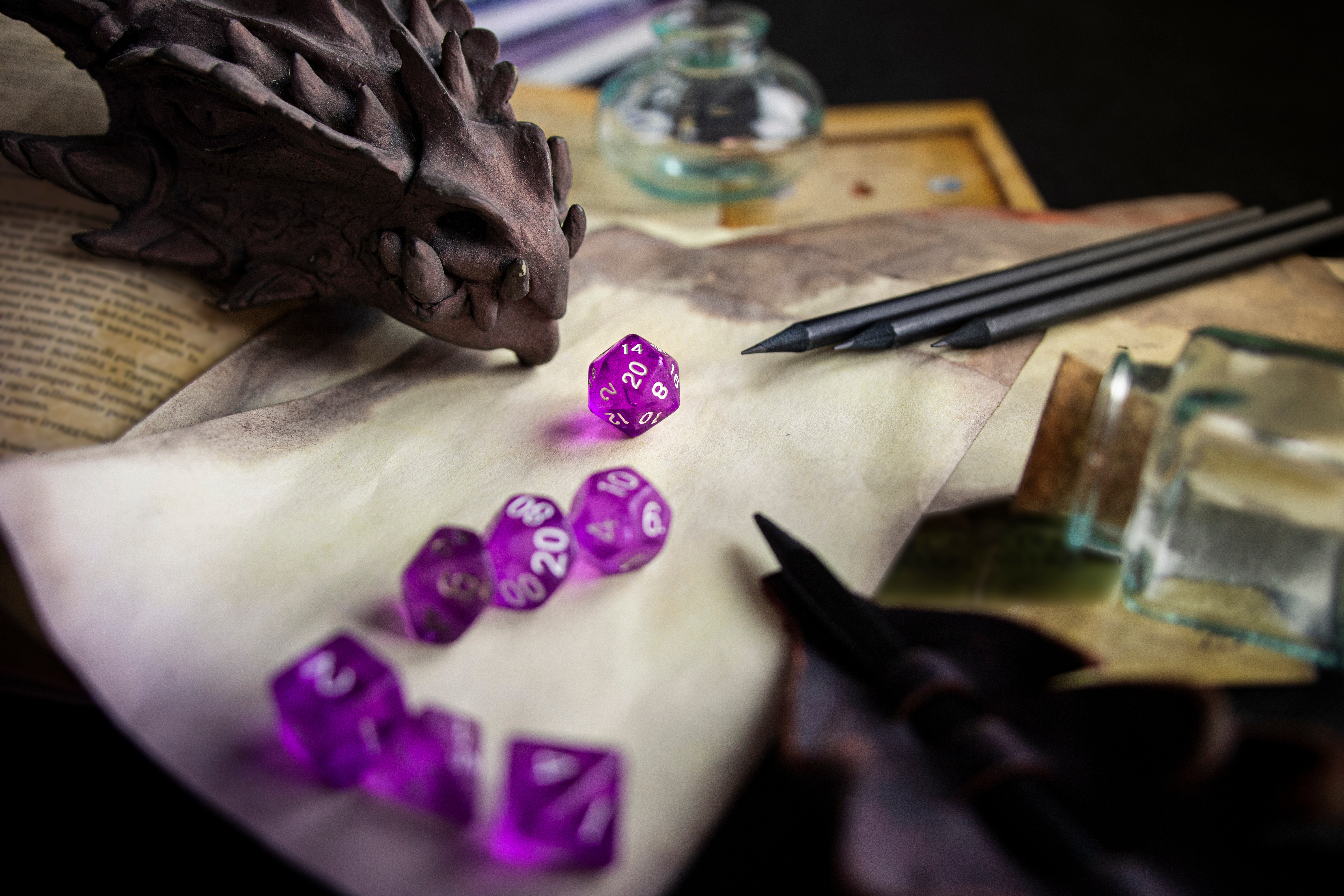 Scattered dnd notes, character sheets, and papers on a table. On top of them are a bright purple set of dnd dice, and a stone dragon head.
